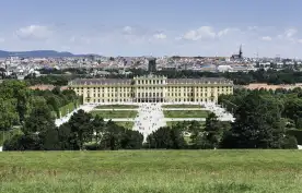 Elevated view of Schönbrunn Palace in Vienna, with the city's skyline in the background. 