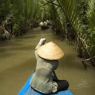 Vietnamese woman rowing a boat on the Mekong River in Vietnam