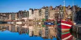 Boats and a row of narrow houses overlooking the Honfleur Harbour in France