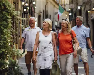 Mature couples looking around old town Italy as evening draws in.  Little lights can be seen outside of the buildings.